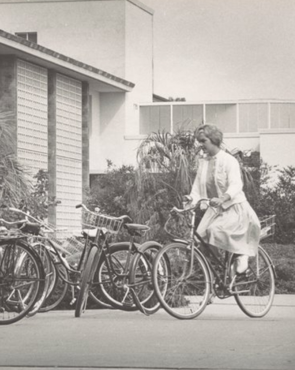 student riding a bike near the library in 1962