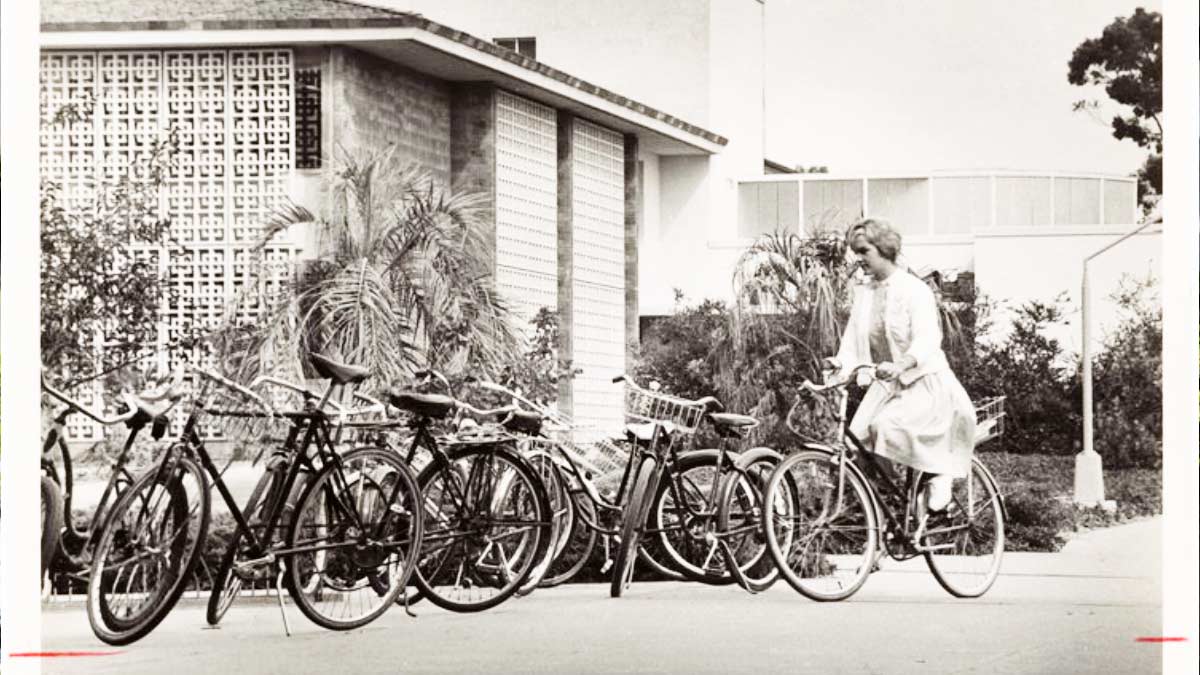 student riding a bike near the library on October 7, 1962