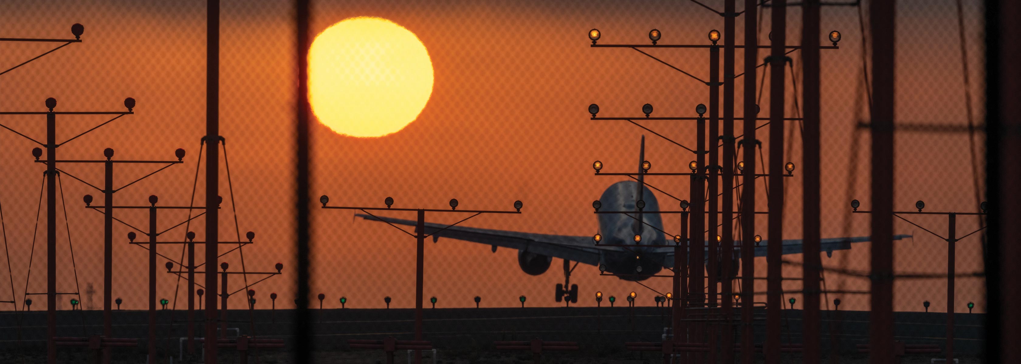 Airplane taking off at sunrise by Glenn Beltz