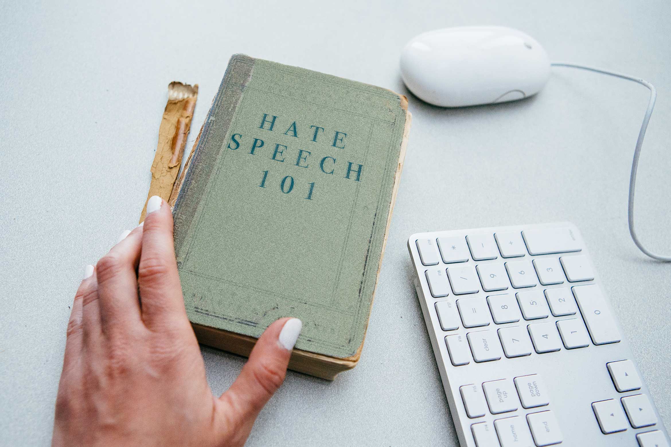 book on table next to computer keyboard called Hate Speech 101