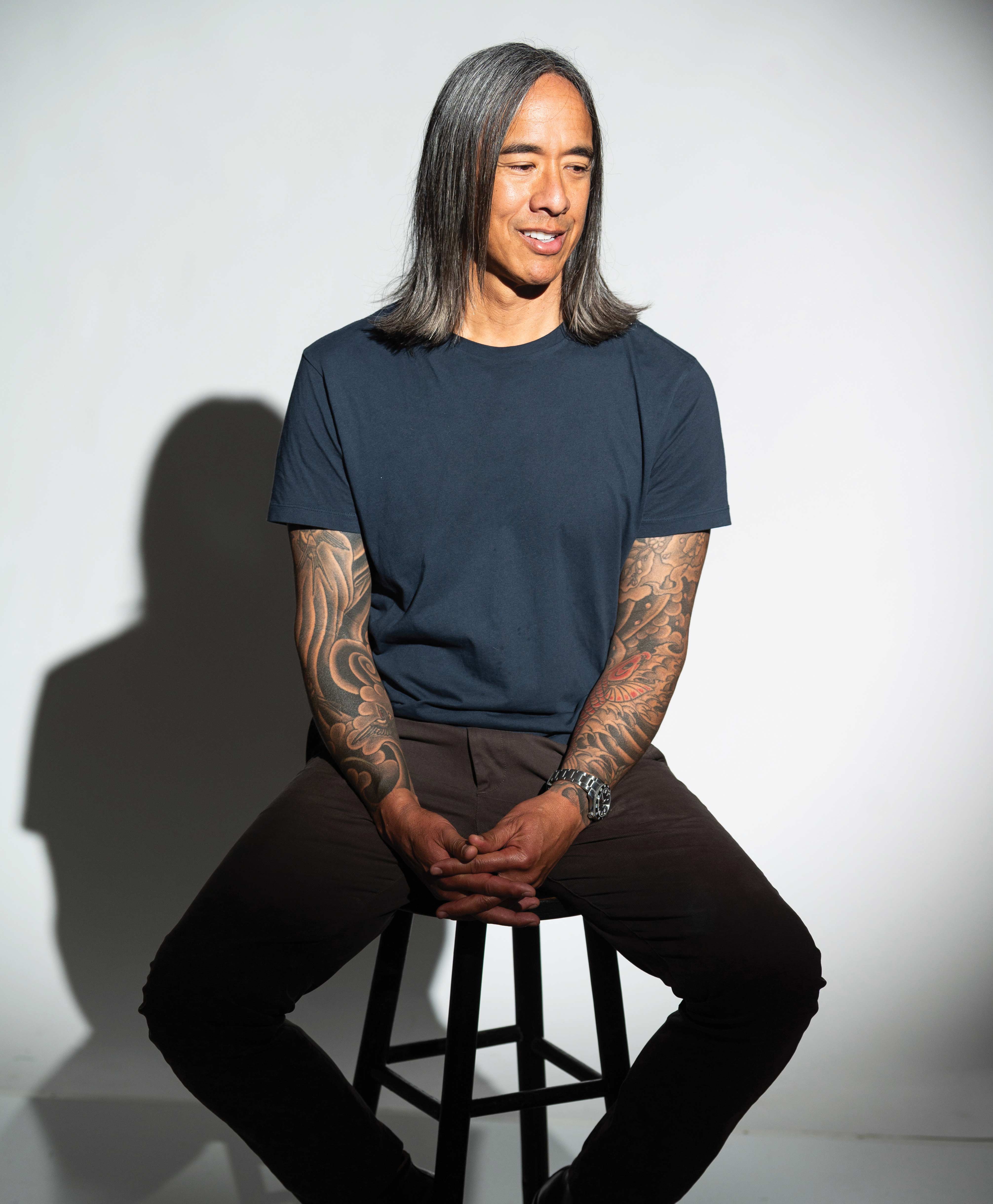 Kip Fulbeck portrait seated on a stool with a white background