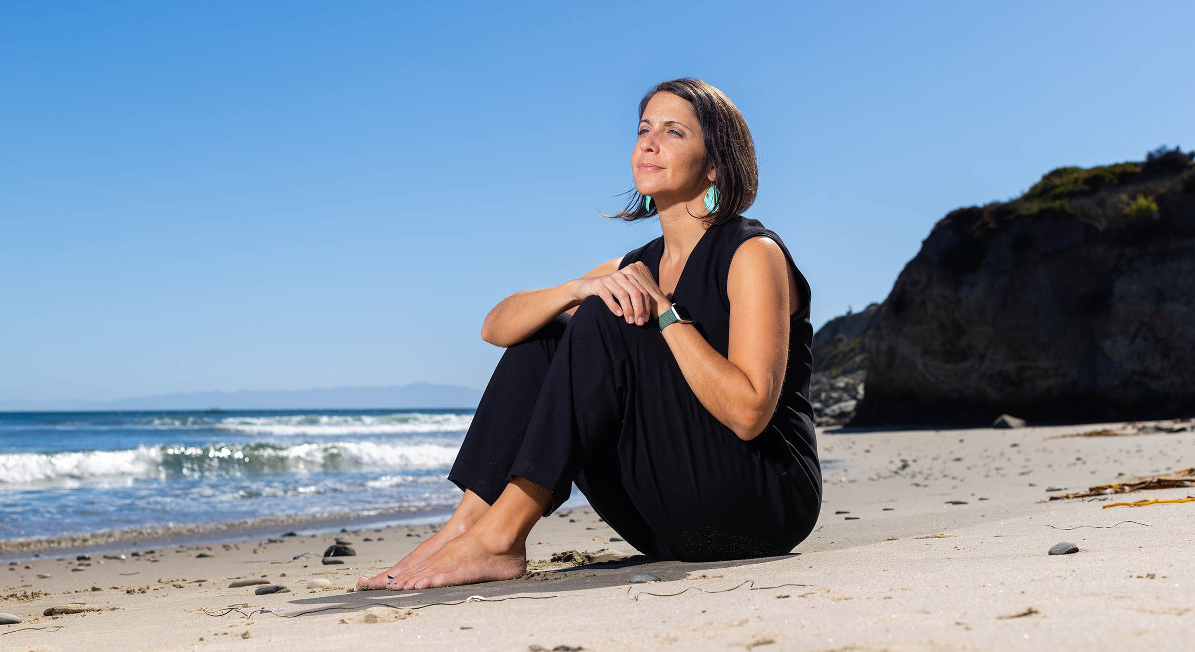 Mona Damluji sitting at Campus Point in the sand
