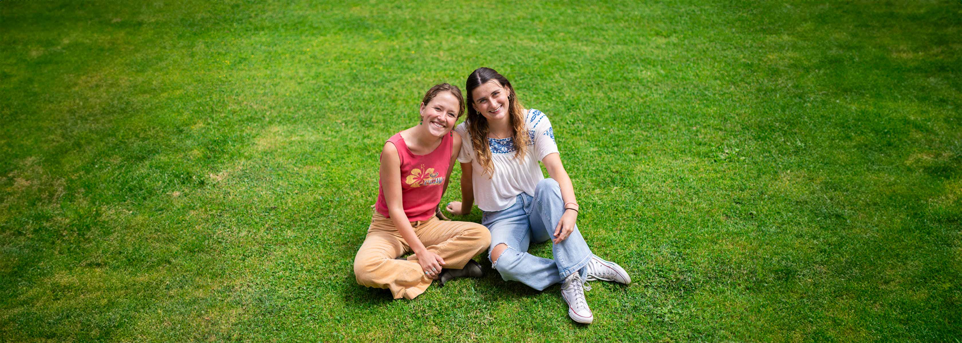 Molly McGee and Eva Mills sitting on green grass