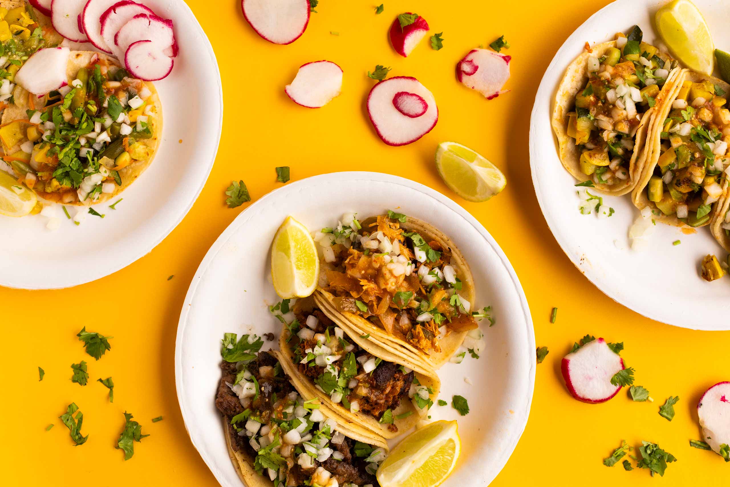 plates full of tacos on bright yellow