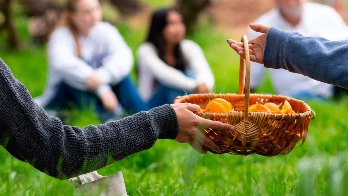 student passing a basket of oranges