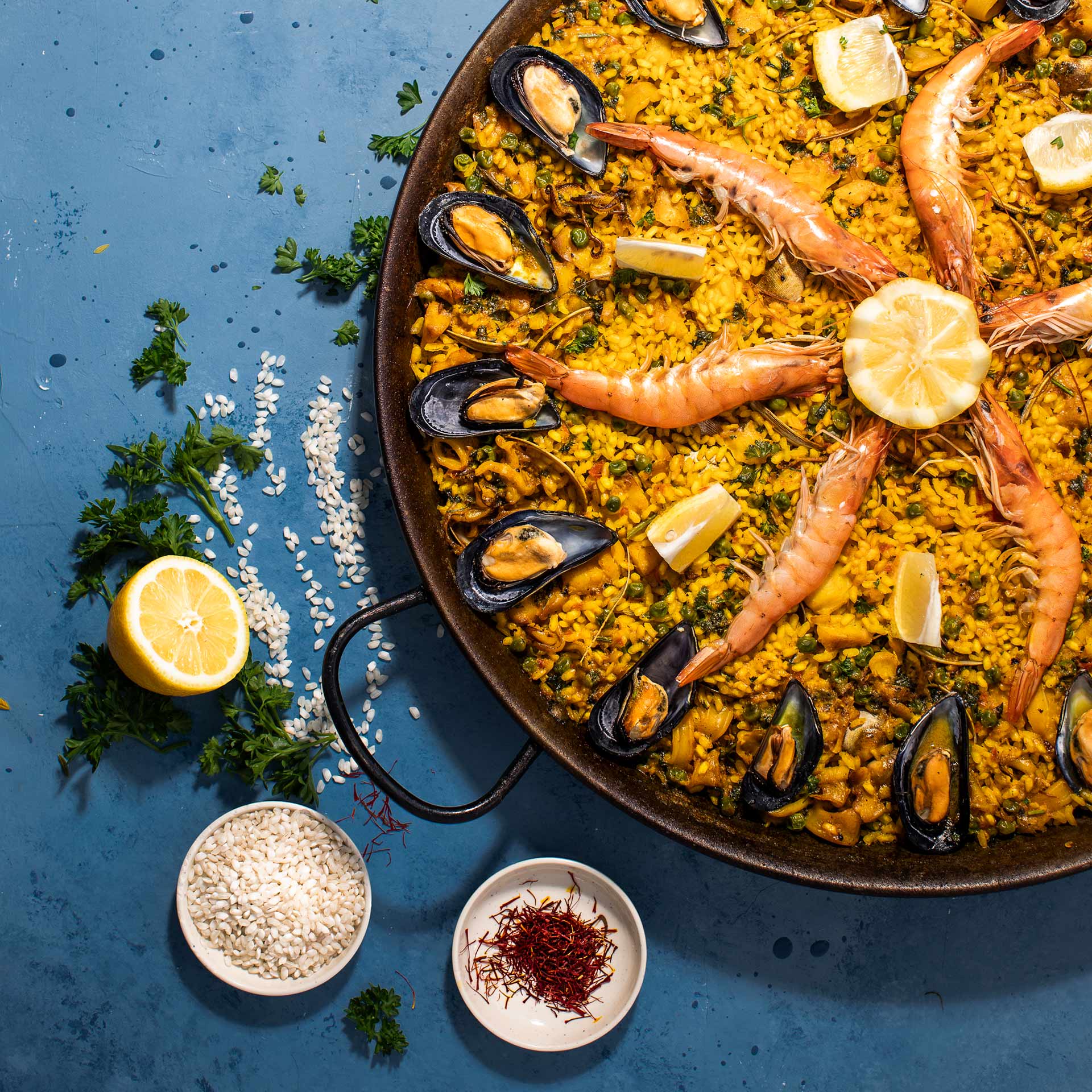 Seafood paella with ingredients on blue background